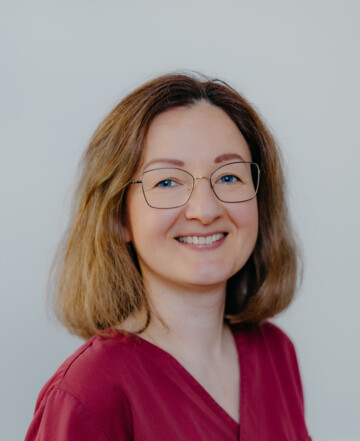 Portrait von Maria Libkina in rotem Kasak vor hellem Hintergrund